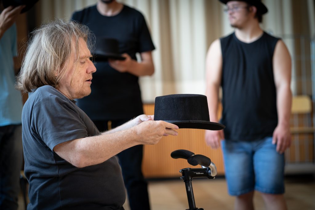 Nahaufnahme: Der Choreograf hält einen Hut nach vorne