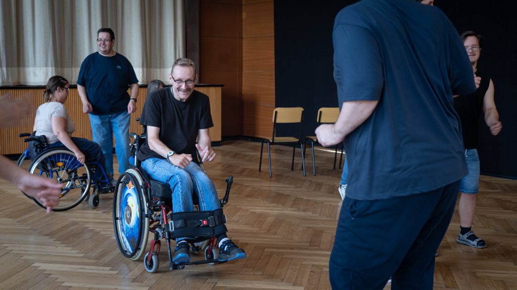 Ein Tänzer im Rollstuhl übt eine Figur und lacht dabei